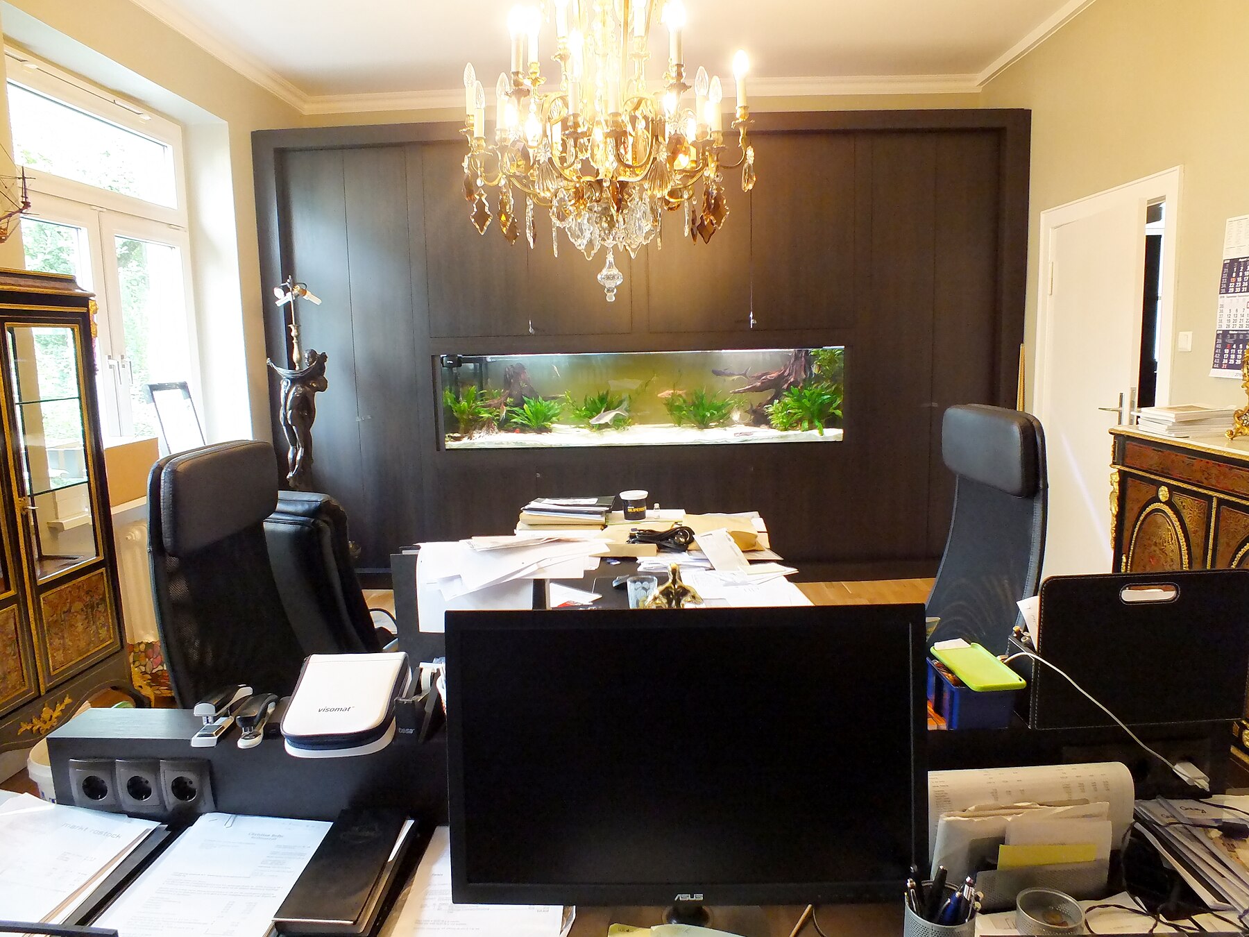 Großes Einbauaquarium in einem Büro mit dunkler Wandverkleidung